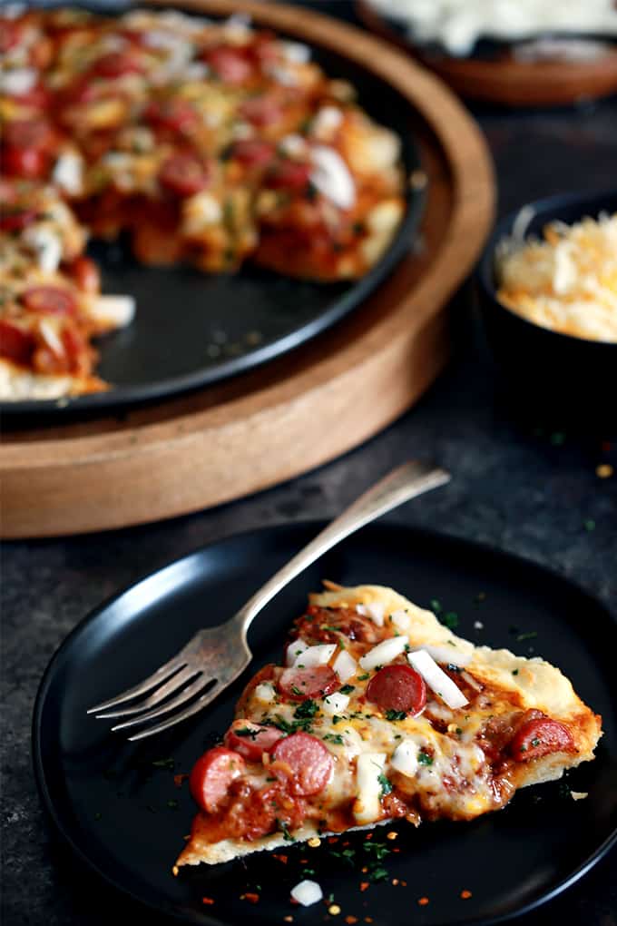 This Chili Cheese Dog Pizza begins with a homemade pizza dough layered with hearty chili and  shredded Mexican cheese before being topped with sliced hot dogs.  It's then garnished with chopped onion and cilantro before being cut into wedges and served.  Easy enough for any weekday, yet the perfect way to kick off a weekend. 