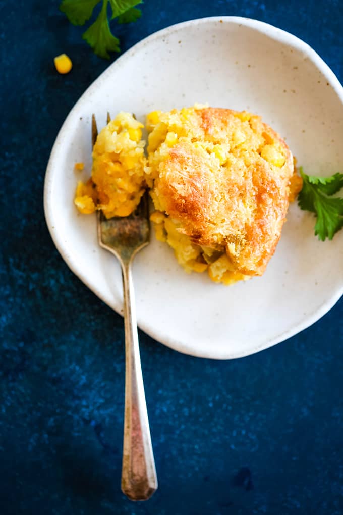 A white plate with a serving of Southwest Green Chile Corn Casserole and a fork.