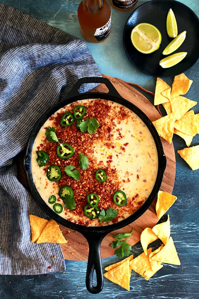 This Sweet Corn Queso with Pepperoni Crumbs literally comes together by just stirring ingredients together with a spoon in a cast iron skillet.  Red onion, garlic, jalapeño and corn are stirred into Monterey Jack cheese to create this incredible queso that's garnished with the most insanely delicious pepperoni crumbs, cilantro and jalapeños.
