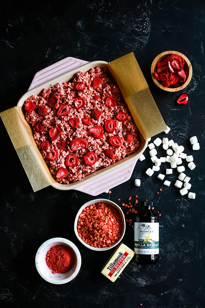 A pan of Strawberry Rice Krispie Treats surrounded by all of the ingredients needed to make them.